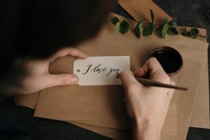 Person crafting a beautiful I love you card with calligraphy, featuring eucalyptus and ink.