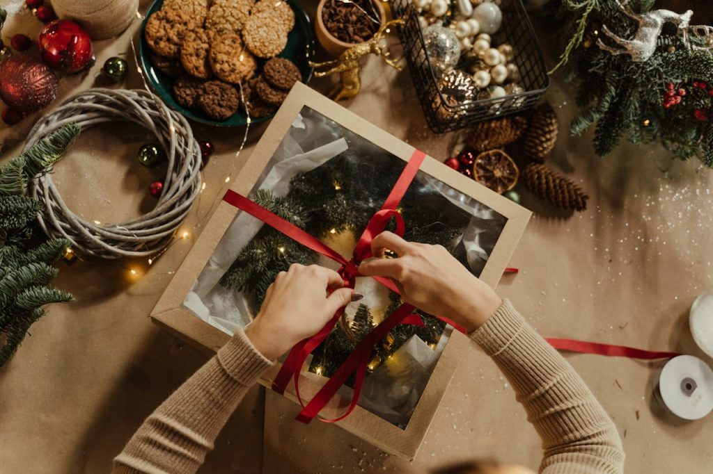 top-view-of-woman-packing-a-christmas-present-6063706 Top view of a Christmas gift wrapping scene with cookies, baubles, and festive decorations.