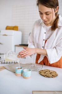 Focused craftswoman pouring wax into molds, exploring candle making art.